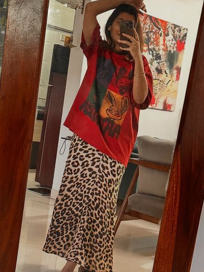Styling a leopard print skirt in three ways. Look 1: Paired with a graphic tee for a pop-up event, showing an edgy, casual vibe.