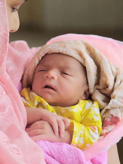 A tender lifestyle moment of a mother holding her sleeping newborn. These at-home sessions are perfect for capturing the real, loving environment of a new family.