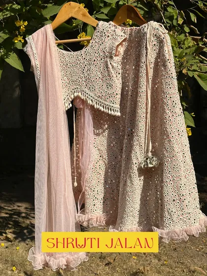 The blush pink mirror-work lehenga. The delicate color and sparkling details make it a dreamy choice for any little girl.