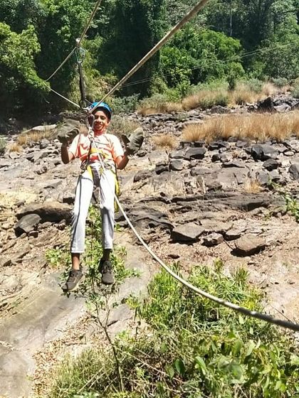 A young boy gives a thumbs-up while crossing the rope bridge, proud of his achievement.