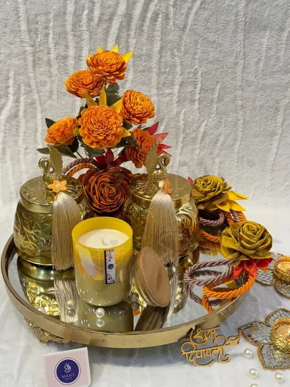 Getting your Diwali gifting sorted is easy with my custom hampers. This arrangement on a golden mirrored tray features scented candles and decorative jars, all in a warm, festive color palette.