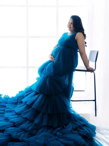An elegant pose with the mom-to-be seated on a high chair, allowing the magnificent blue gown to cascade to the floor.