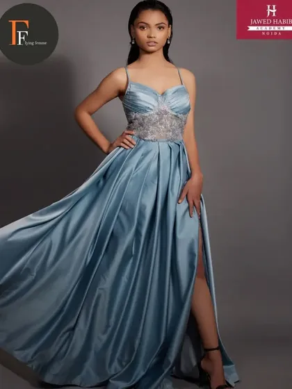 A model in a flowing blue satin gown, looking ethereal with makeup and hair by our students.