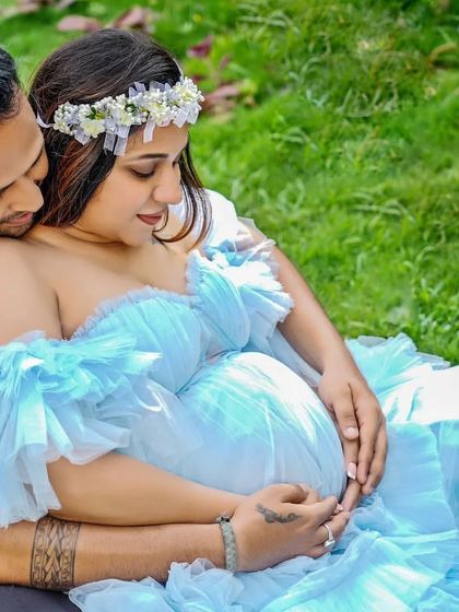 An intimate close-up of a couple during their maternity shoot. The mom-to-be is wearing a light blue ruffled gown, showing the delicate off-the-shoulder detail.
