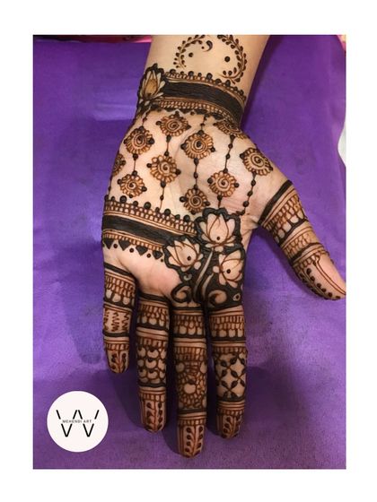 A close-up of the hand with hanging lotus motifs.