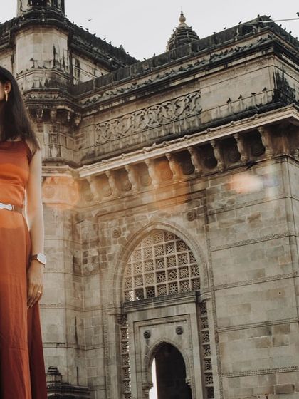 A beautiful, sun-flared shot of a couple at the Gateway of India, capturing the golden hour light.