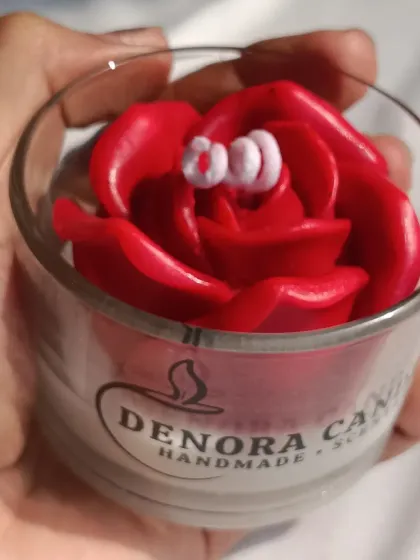 A close-up of the red rose jar candle, showing the detailed petals and curled wick.