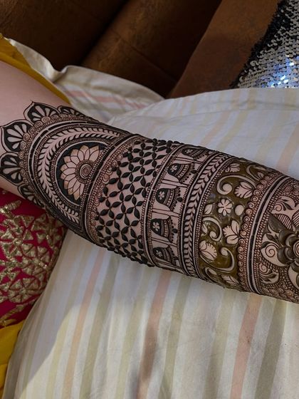 An arm covered in beautiful bands of different patterns, including elephants, geometric shapes, and floral vines.