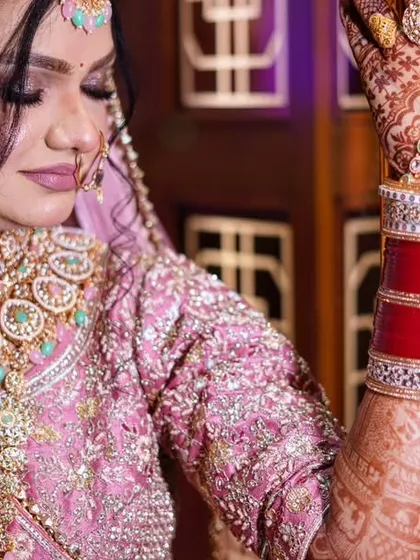 This portrait focuses on the bride's stunning jewelry and the rich texture of her pink lehenga, showing off the craftsmanship of her wedding attire.