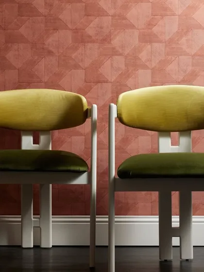 A captivating trompe l’oeil wallpaper named "Clay" by Nobilis, which creates the illusion of glossy tiles through a matte, finely ridged texture. Paired with velvet-upholstered chairs, it showcases an innovative blend of texture and illusion.