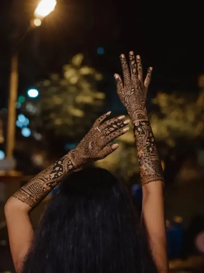A beautiful shot of a bride showing off her full-arm mehndi at night. The design truly becomes a part of the celebration.