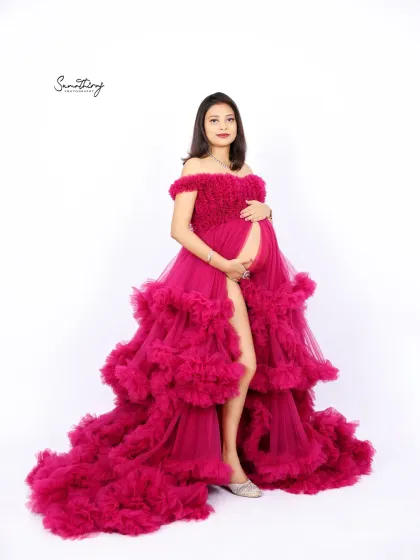 A powerful and glamorous portrait of a mother-to-be in a magenta ruffled gown. The pose highlights the stunning design of the dress and her confident glow.