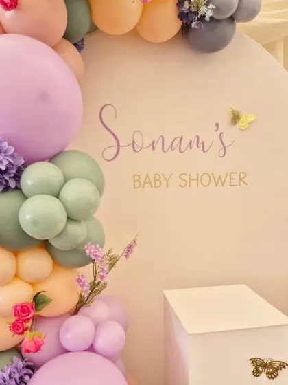 A detailed shot of the personalized "Sonam's Baby Shower" backdrop, showing the delicate script and butterfly accents.