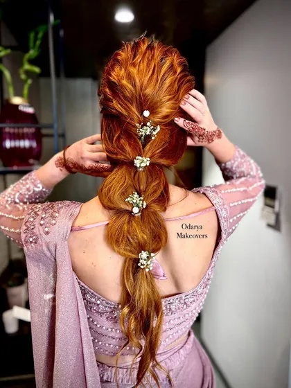 A modern and chic mermaid braid for a party or pre-wedding event. The bubble-like sections are adorned with baby's breath, and the style looks amazing on colored hair.