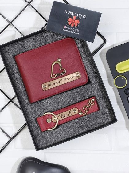 A maroon leather wallet and keychain set, both featuring a 'love' charm.
