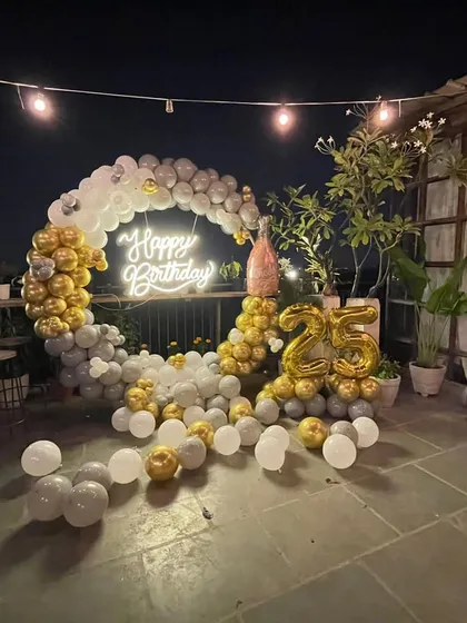 A closer look at the 25th birthday balloon arch, showing the details of the arrangement and the glowing neon sign. The open-air setting adds to the celebratory feel of the event.