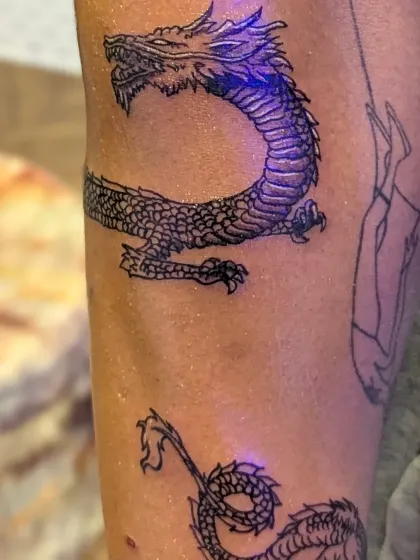 A closer look at the fine line details and shading on the scales of the wrapping dragon tattoo. Even in a simpler style, precision is key to making the design stand out.
