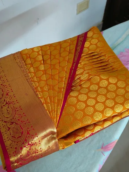 Another view of the perfectly pre-pleated yellow silk saree. This ready-to-drape solution is ideal for anyone who finds saree draping challenging or time-consuming.