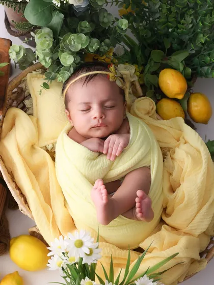 A bundle of sunshine. This swaddled pose from our lemon-themed shoot is perfect for newborns. The bright yellow wrap and fresh lemons create a cheerful and unique portrait of your sleeping baby.