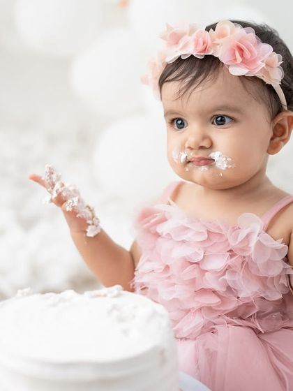 "What is this stuff?" A funny and adorable moment from a cake smash session, with the birthday girl looking at her frosting-covered hands.