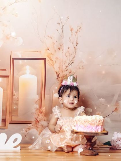 A magical first birthday moment. This little princess is surrounded by soft lights and candles in a dreamy, ethereal studio setup.