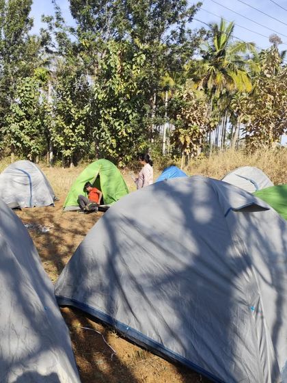 A view of our campsite with multiple tents pitched in a field. We provide all the necessary camping gear.