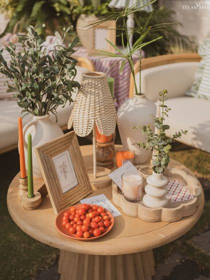 A styled coffee table featuring a wicker lamp, fresh cherry tomatoes, and other rustic details.