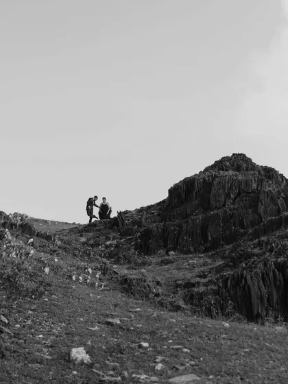 A minimalist black and white wide shot of the couple on a vast, rocky landscape, emphasizing their connection in the midst of the grand outdoors.