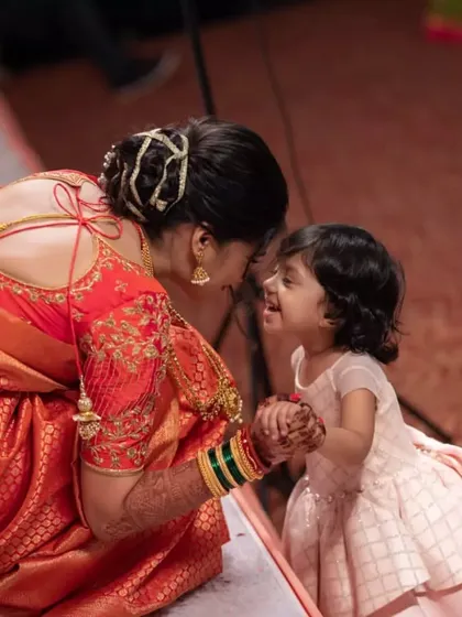 A heartwarming moment between the bride and a little one. This photo also gives a great view of the back of her hairstyle, a neat bun with a golden accessory, perfect for a Maharashtrian bride.