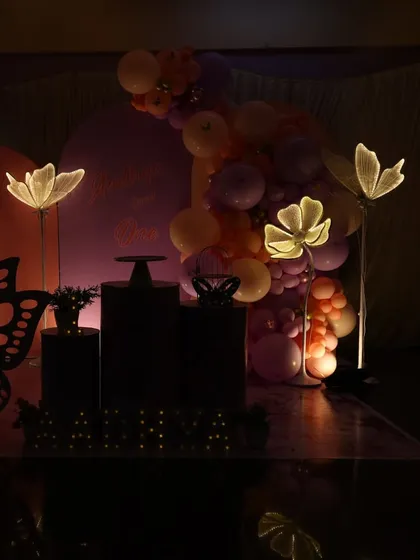 A nighttime view of a butterfly garden setup, showing how the illuminated flower and number props create a magical glow.