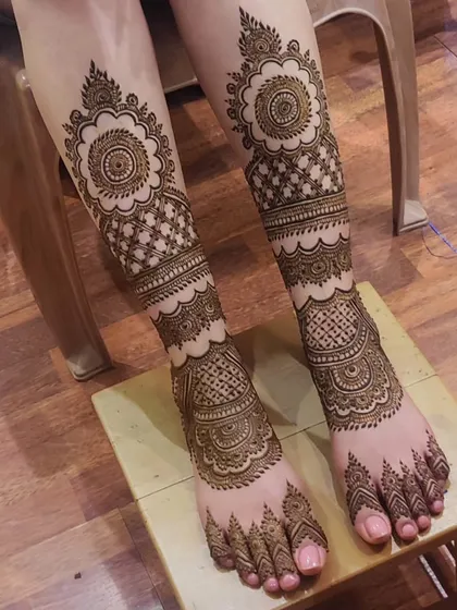 A full-leg mehendi design with multiple bands of different patterns. The large floral mandala at the top is the centerpiece of this stunning work.