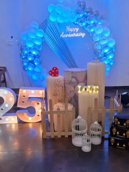 A different angle of the 25th-anniversary setup, showing the decorative props like birdcages and vintage-style trunks.