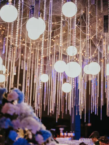A ceiling of cascading light strings and glowing orbs creates the feeling of a starry night sky, transforming the Sangeet venue into a magical, luminous space.