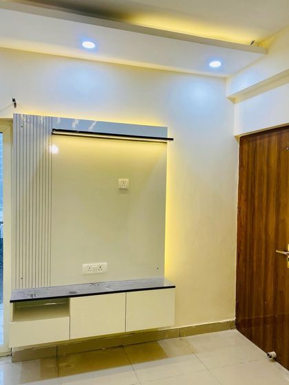 A compact, floating TV cabinet in white, with a marble-finish top and a small fluted panel detail. The backlighting adds a soft glow.