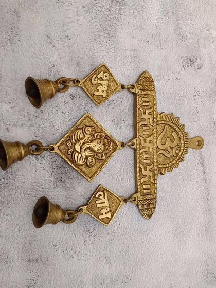 A brass wall hanging with Om, Gayatri Mantra, Ganesha, and "Shubh Labh," a complete package of blessings for your entrance.