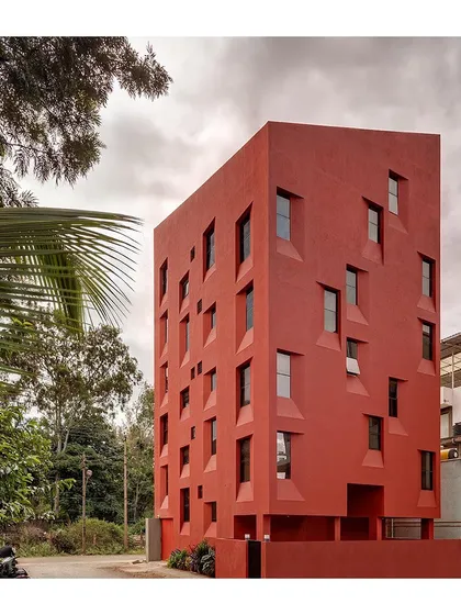 The "Stacked Student Housing" building seen from the street corner, showcasing its unique, angular form and the rhythmic pattern of its fenestration. The design makes a strong statement on a very small footprint.