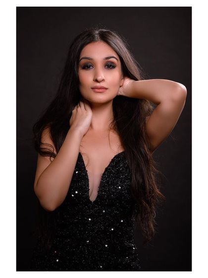 A glamorous studio portrait in a sparkling black dress. The lighting and pose create a sophisticated and elegant look.