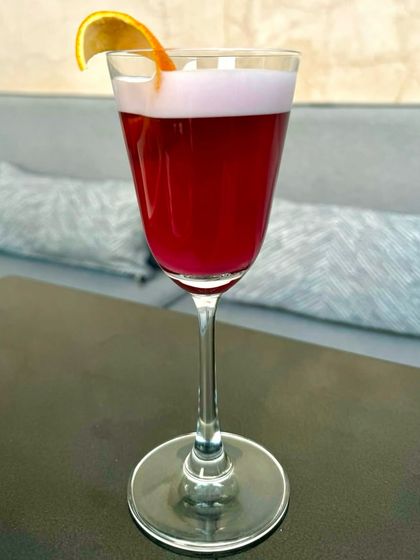 A vibrant, deep red cocktail with a delicate foam top, showcasing our flair for creating visually stunning and delicious drinks.