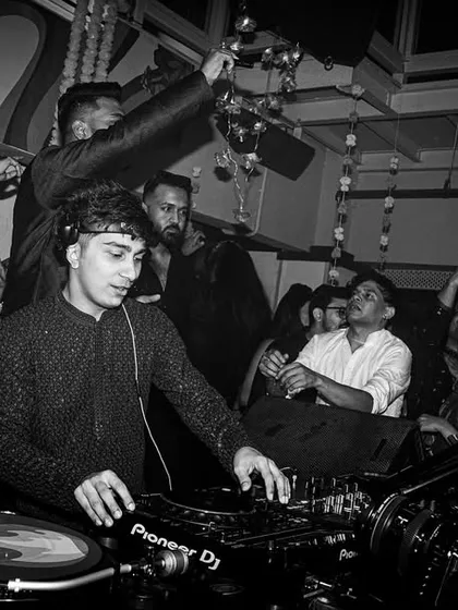 A black and white photo from the same Diwali party. It captures me focused on the mix while the crowd is celebrating all around me.