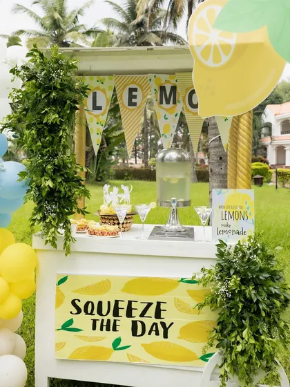 A "Squeeze the Day" lemonade cart, complete with a beverage dispenser and fresh greenery.