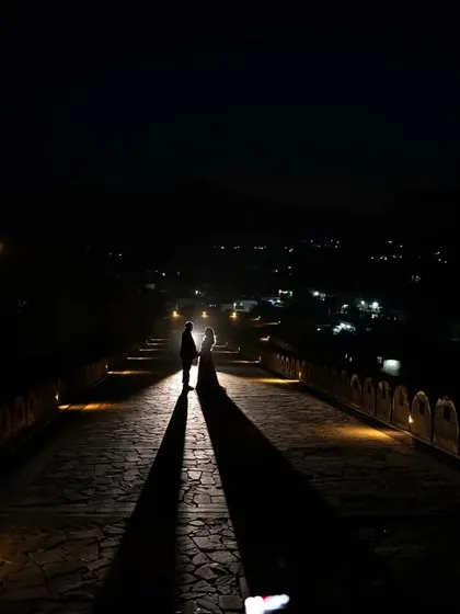A stunning long shot of the couple walking down the illuminated ramp of the fort at night. The dramatic shadows and grand scale of the location make for an epic and memorable photograph.
