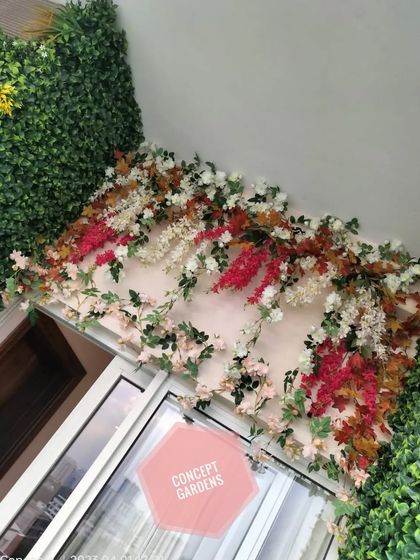A detailed look at the artificial floral arrangement above the balcony door, featuring a mix of red, white, and autumnal colors.