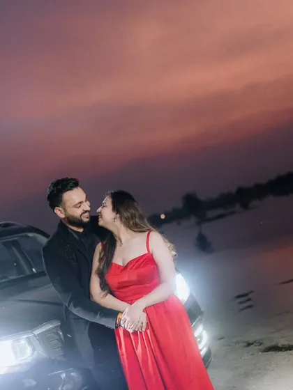 A modern and stylish night-time pre-wedding photo. We used the car's headlights and the dramatic twilight sky to create a moody, cinematic scene that feels like a still from a movie.