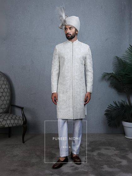 A full frontal view of the ivory sherwani, showing the intricate embroidery and beadwork. This is more than clothing; it is a cherished memory in the making.