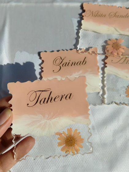 A set of custom resin fridge magnets with names and preserved flowers. The soft peach and white design is very delicate.