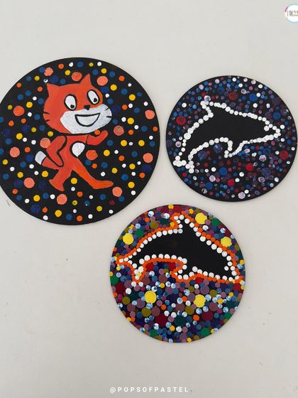 The finished dot-painted coasters, featuring a fun cat and dolphin designs. A great handmade gift idea.