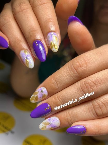 I love this bold combination of vibrant purple and hand-painted golden florals. The contrast is stunning, and the tiny gold studs add just the right amount of detail to this artistic manicure.