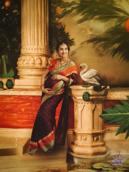 A serene portrait set against a painted backdrop of a palace garden. The mom-to-be leans against a pillar, creating a regal and artistic maternity image.