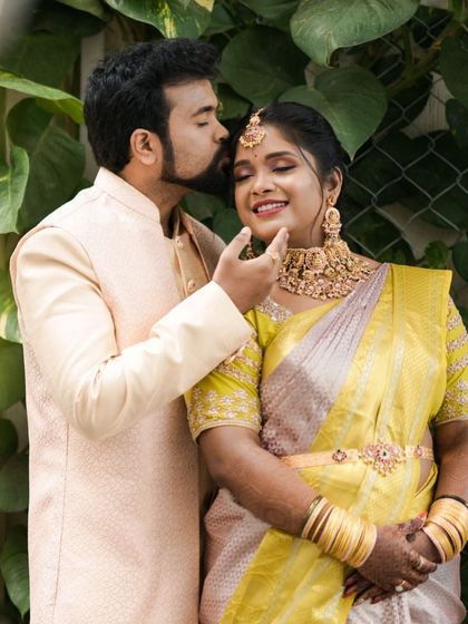 A tender moment between our client Sheethal and her husband. Her beautiful temple-style vaddanam (waist belt) is perfectly visible, cinching her saree and completing her look.