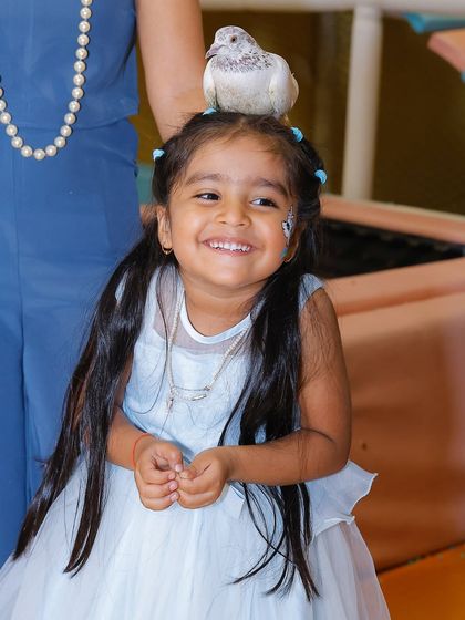 A birthday girl smiles, delighted by the magic show's live dove. These gentle animal interactions are always a memorable part of our parties.